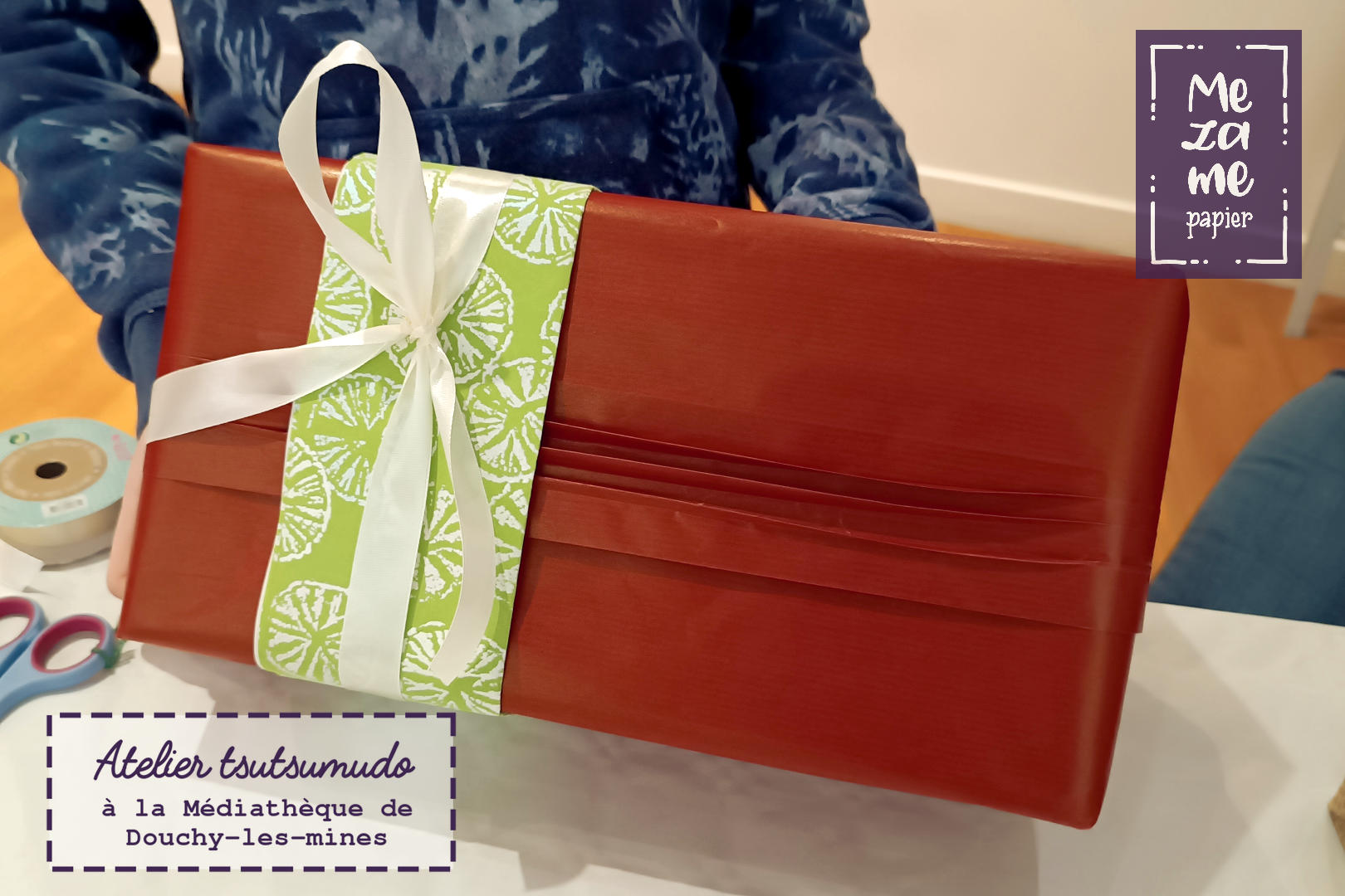 Cadeau emballé dans du papier kraft rouge avec un accent de papier japonais vert fluo décoré de tranches d'agrumes irisées