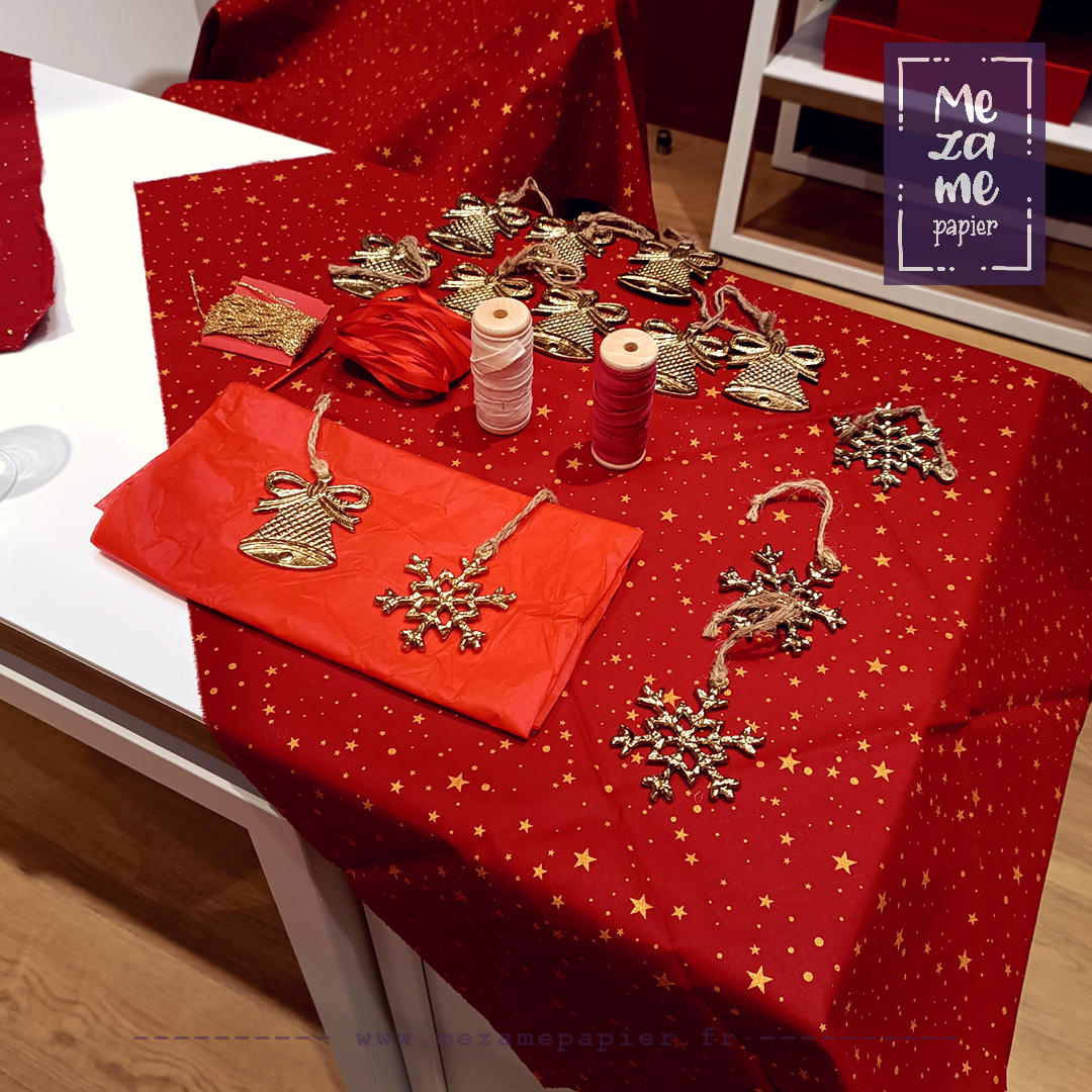 Station de travail avec tissus rouges décorés et ornement pour emballage cadeau à la japonaise : breloques métalliques, différents fils de coton, velours, jute, etc...